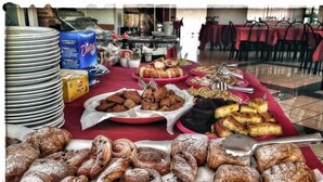 Una mesa de buffet con diversos pasteles y platos, incluyendo pan y postres, con platos y cubiertos sobre la mesa.