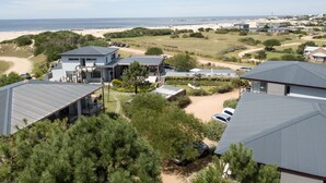 A coastal residential area with houses, a beach, and a lighthouse in the distance.
