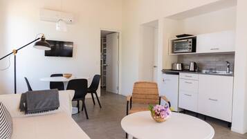 A compact living space with a kitchenette, a dining area with a table and chairs, and a sofa with a blanket.