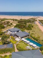Una propiedad frente al mar con piscina, paneles solares y vista al océano.
