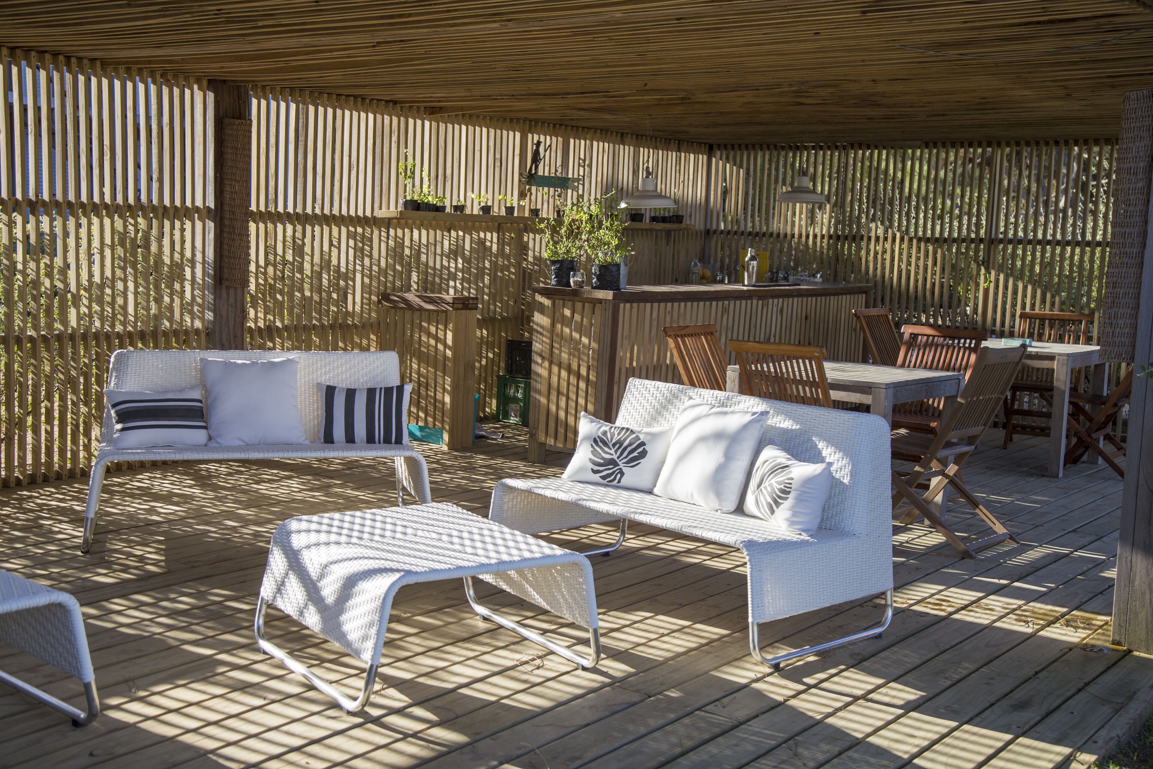 An outdoor patio with wicker furniture, a bar area, and a wooden deck.