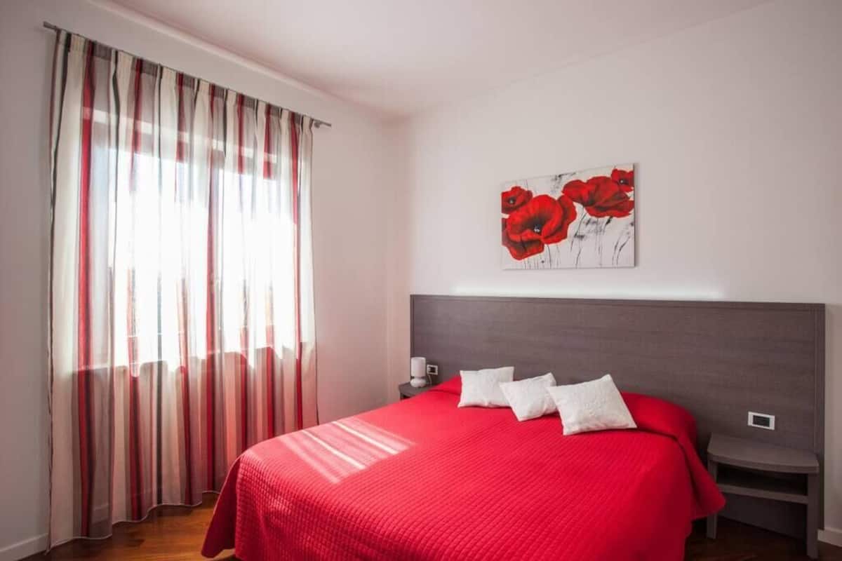 Ein Schlafzimmer mit einem großen Bett, einem Nachttisch, Vorhängen und einem Fenster.
