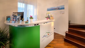 Una recepción con diseño verde y blanco, un logotipo y un ventanal con cortinas.