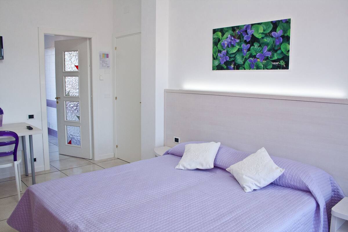 Ein Schlafzimmer mit einem Bett, zwei Kissen, einem Schreibtisch und einem Sessel.