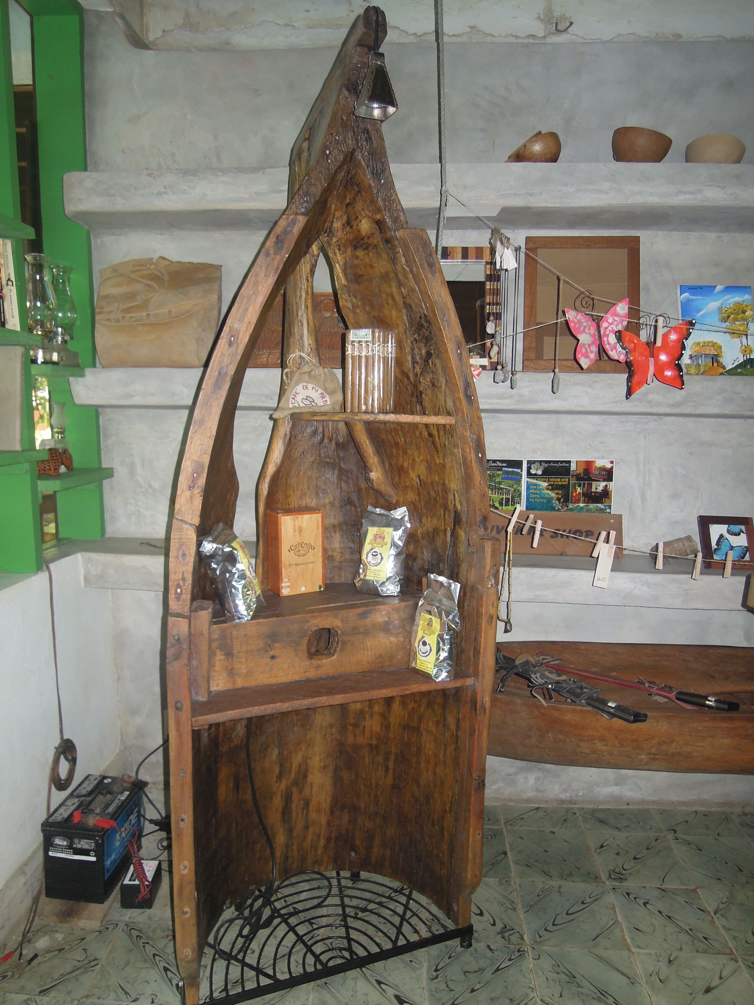 A wooden display stand with various items including a bag of coffee, a box, and some bags hanging on a string.