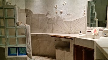 Features a curved vanity with a large mirror and a stone sink.