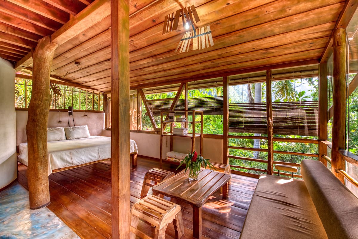 A wooden cabin with a bed, a dining table, and a sofa.