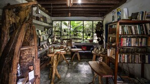 A rustic room with wooden furniture, a bookshelf, and a window with a view of greenery.