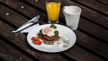 Un plato de desayuno con tostadas, huevo, tomate y una flor blanca sobre una mesa de madera.