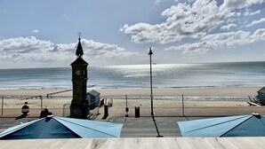 A beach with a clock tower, a lifebuoy, and a blue tent. - The Waterfront Inn (Shanklin)