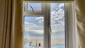 A window with a view of a beach, curtains, and a door handle. - The Waterfront Inn (Shanklin)