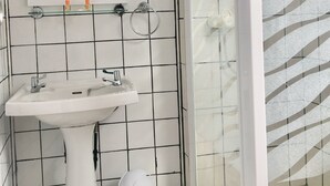 A bathroom with a white sink, mirror, and shower area.