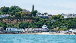 A coastal town with a prominent church spire, beachfront properties, and a sandy beach area.
