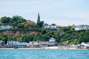 A coastal town with a prominent church spire, beachfront properties, and a sandy beach area.