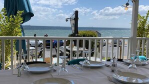 An outdoor dining area with tables set for two, overlooking the sea.