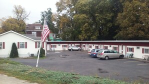 Un motel avec un parking, plusieurs voitures garées et un mât sur lequel flotte un drapeau américain.