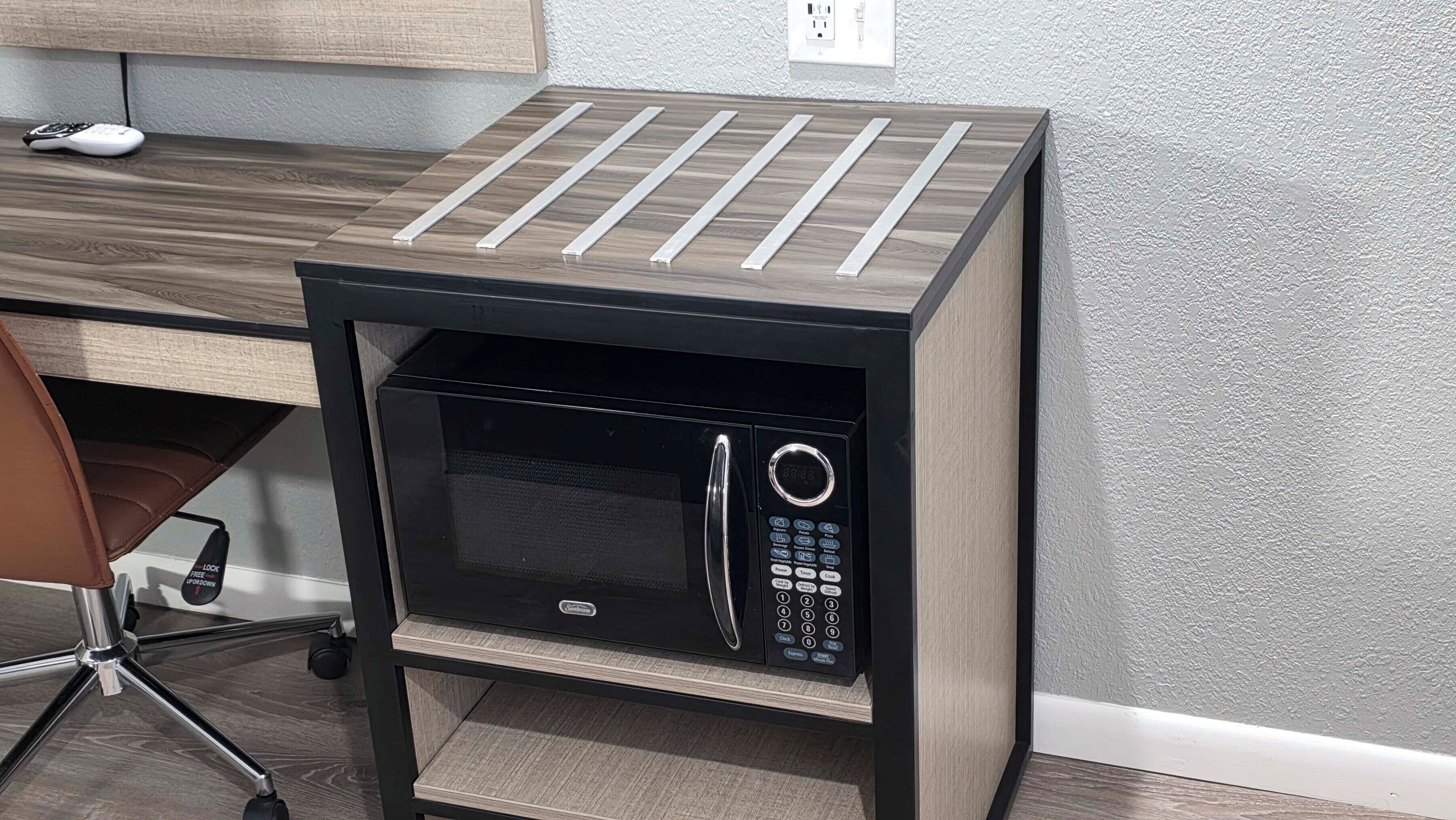 A microwave oven on a wooden stand with a control panel and a power button.