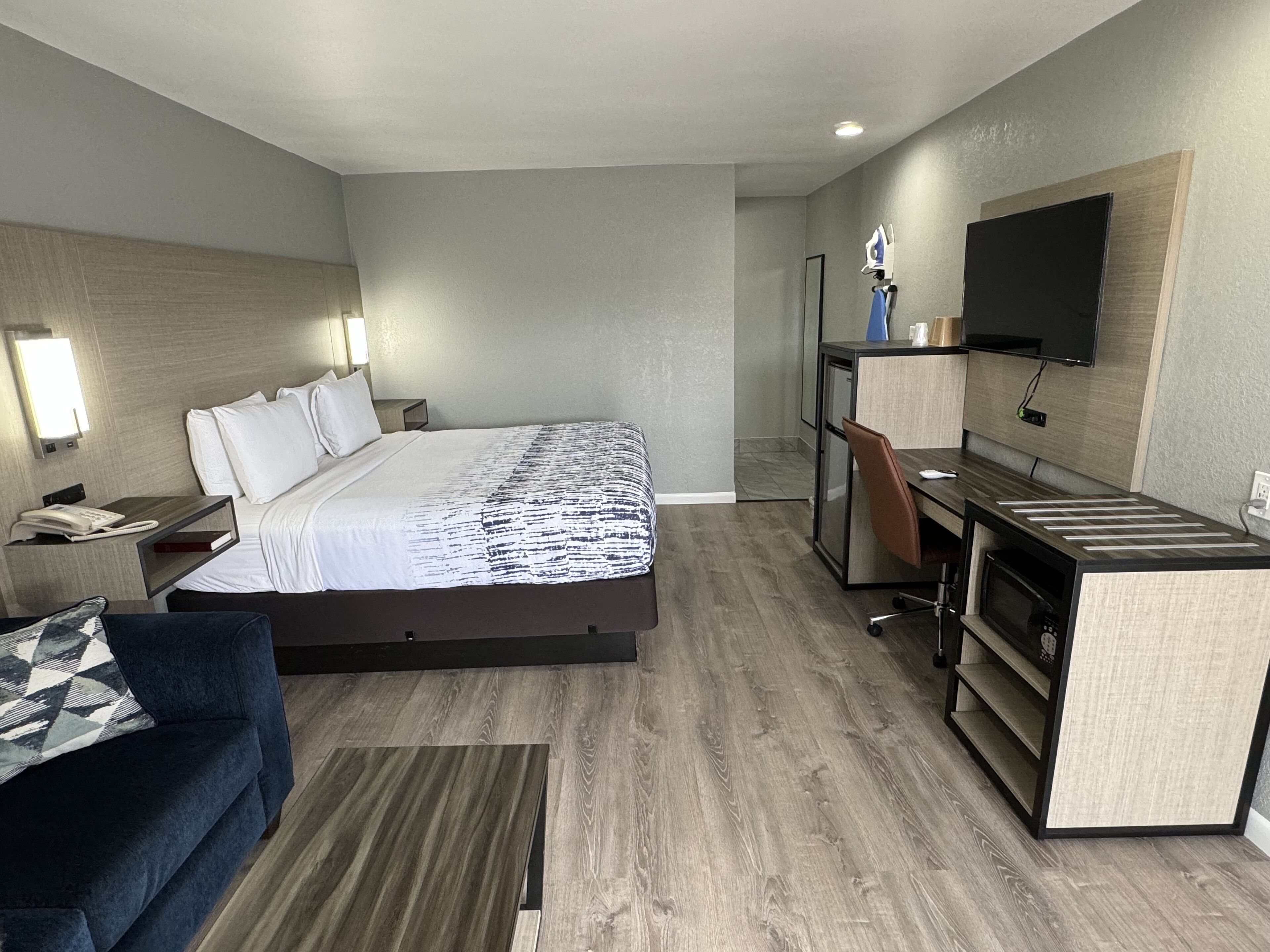 Una habitación de hotel moderna con cama, escritorio, televisor y sofá.