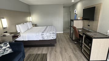 Una habitación de hotel moderna con cama, escritorio, televisor y sofá.