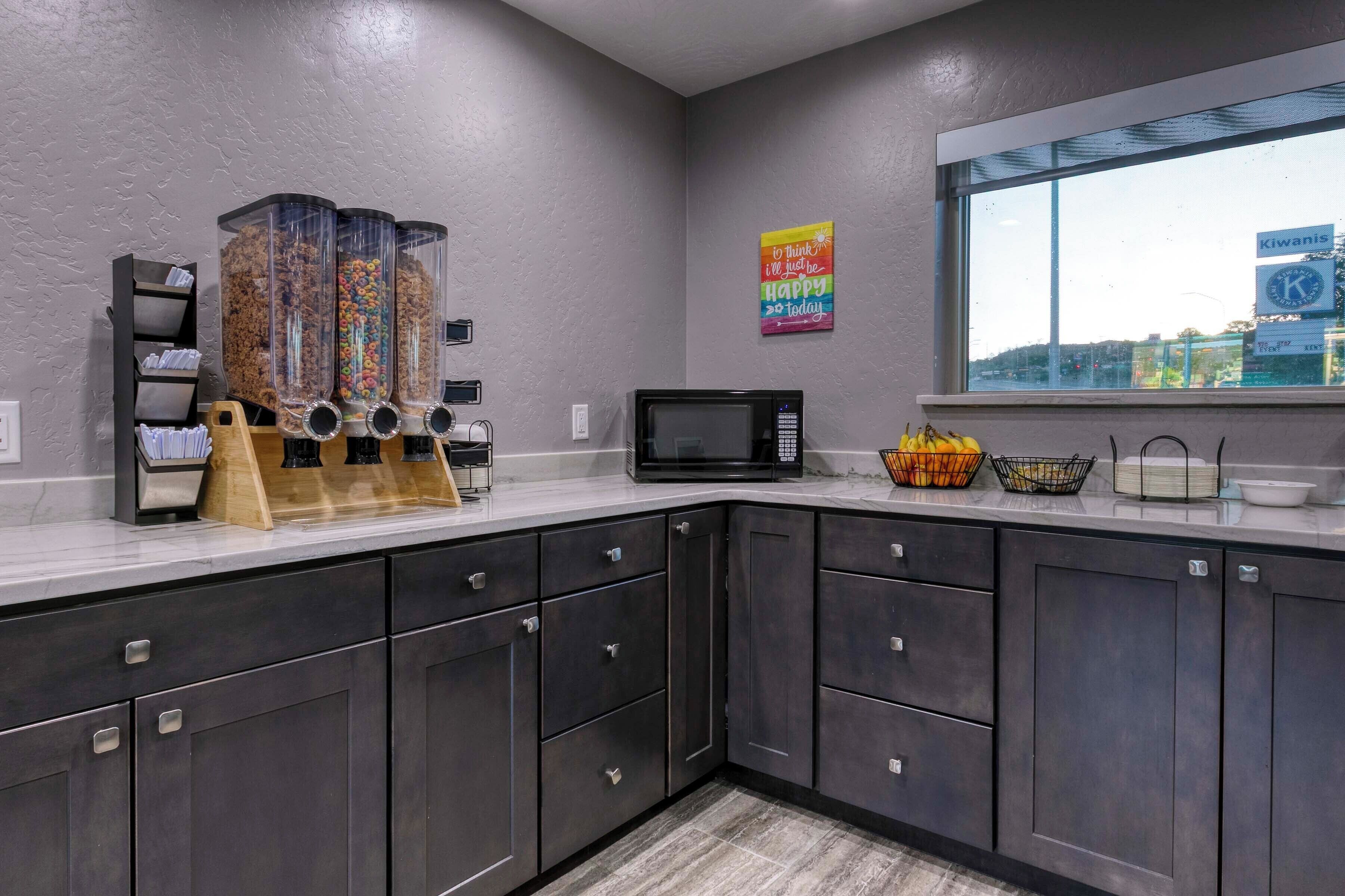 A kitchen with dark cabinets, a microwave, and a fruit basket.
