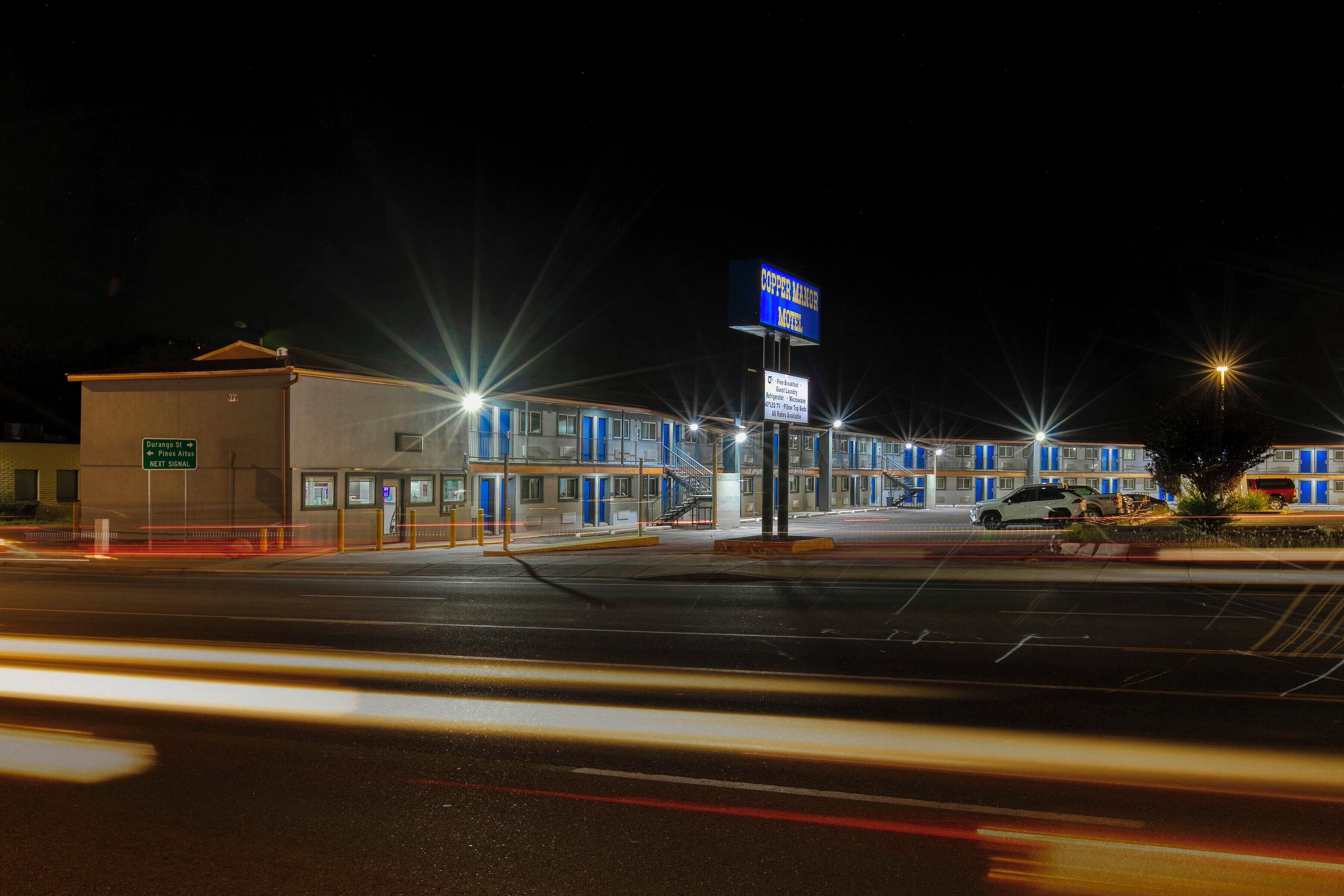 A motel with a prominent sign, a parking lot, and a building with multiple doors.