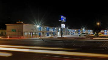 A motel with a prominent sign, a parking lot, and a building with multiple doors.