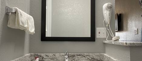A bathroom with a marble sink, a mirror, a towel rack, and a hairdryer.