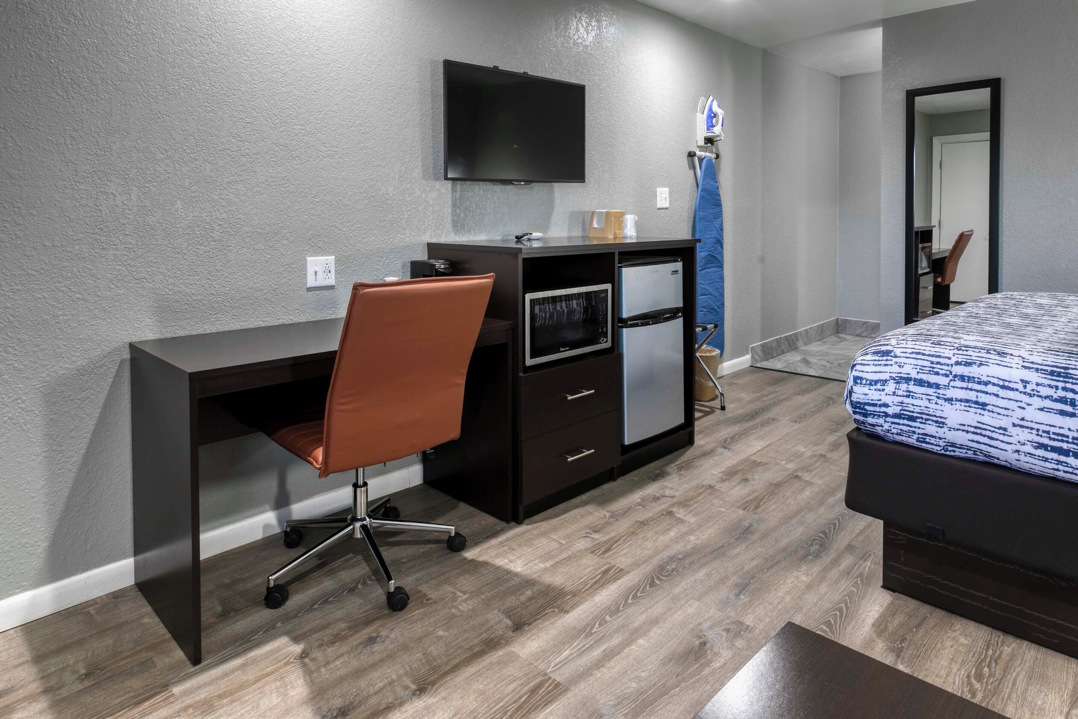 Une chambre à coucher comprenant un lit, un bureau avec une chaise, une télévision et une armoire.