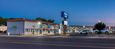 A motel with a signboard, a parking lot, and a street view.