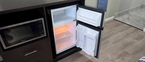 Una kitchenette compacta con microondas, refrigerador y horno pequeño.