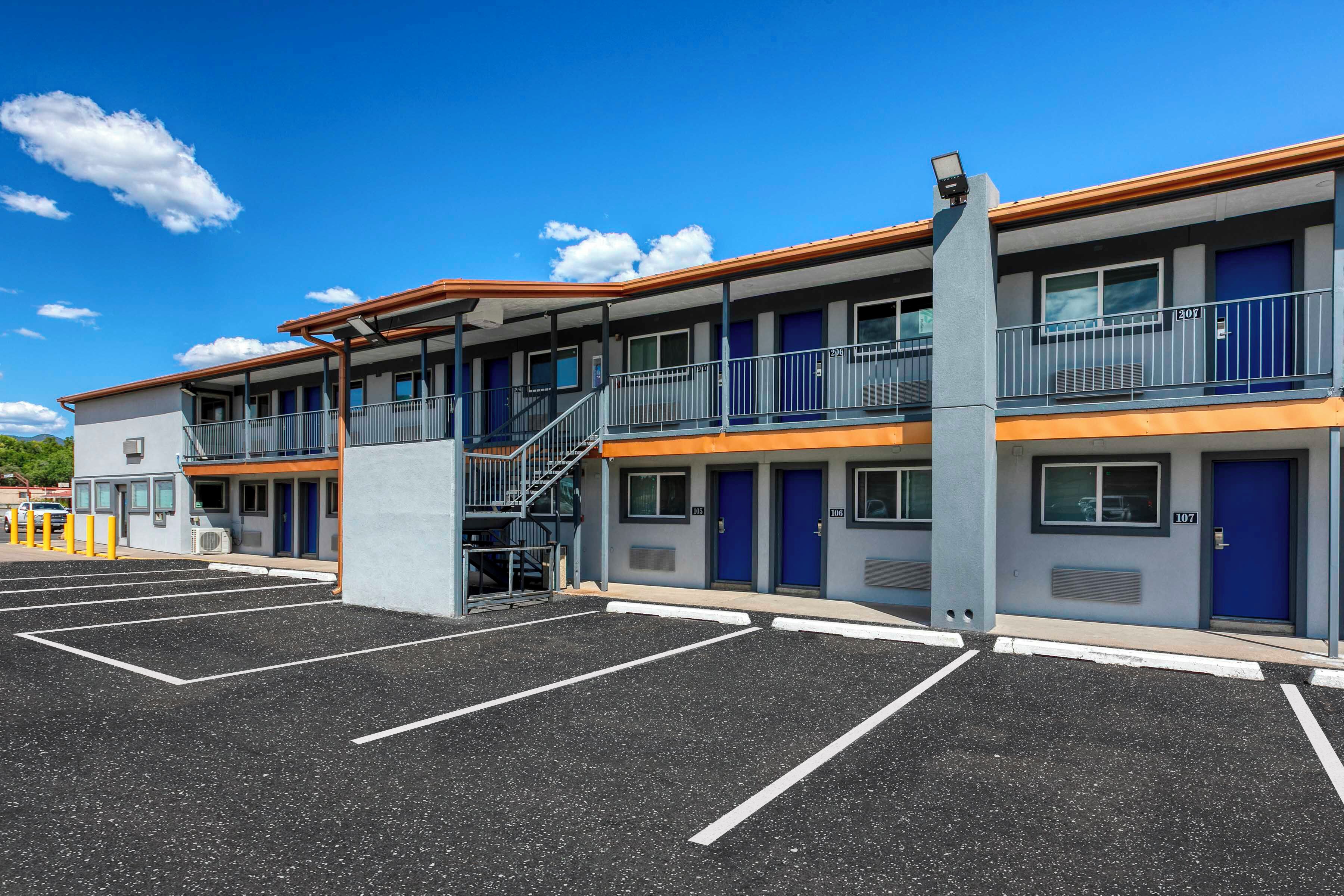 Un motel con una estructura de dos pisos, un área de estacionamiento techada y una escalera al nivel superior.