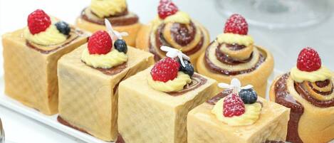 Variedad de postres en un plato blanco, incluyendo pasteles cuadrados y redondos con frutas.
