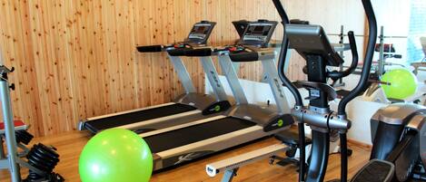 A gym with treadmills, an elliptical, and a green exercise ball.