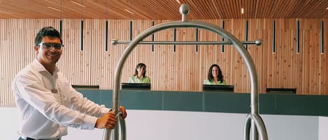 A person holding a metallic structure in a modern interior with wooden paneling and a green accent wall.