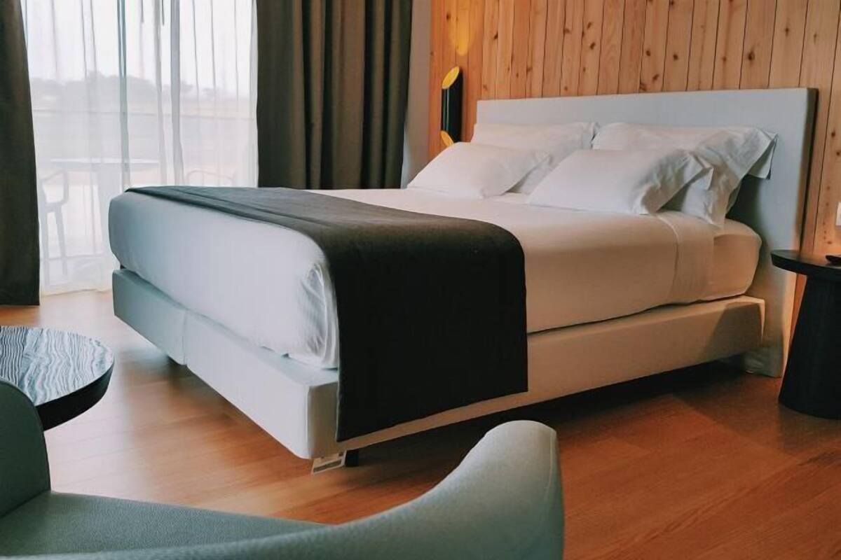 A modern hotel room with a bed, a chair, and a wooden floor.