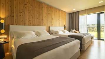 Quarto de hotel com duas camas, painéis de madeira nas paredes, uma janela grande com vista e uma mesa de cabeceira com abajur.