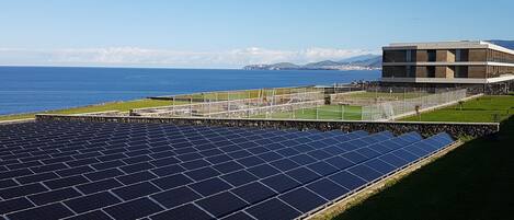Solar panels, a building, and a coastal view.