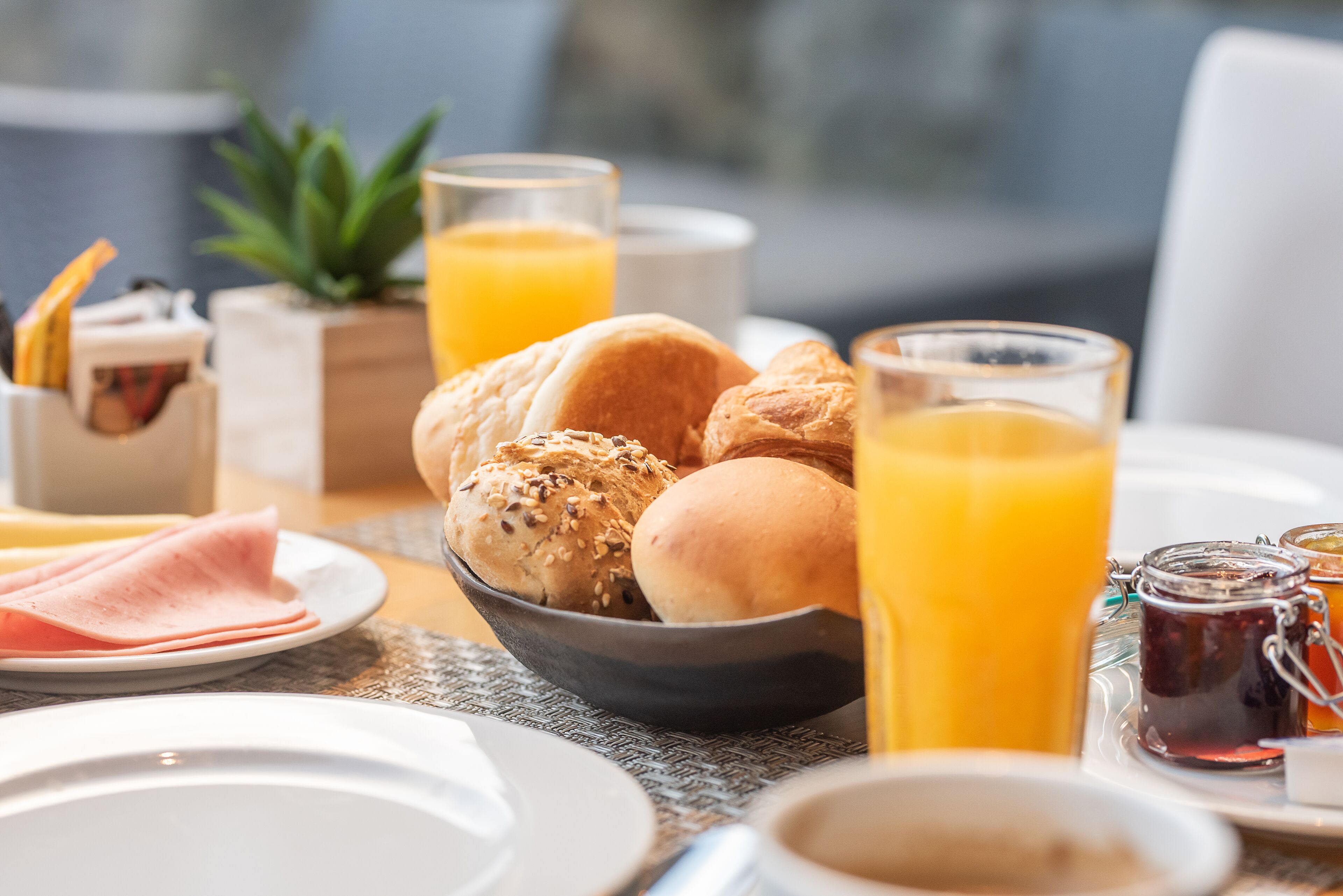 A breakfast setting with bread, ham, and juice.