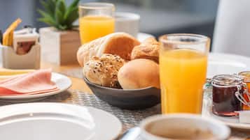 A breakfast setting with bread, ham, and juice.
