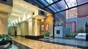 Eine geräumige Lobby mit hochglänzendem Boden, großen Fenstern und moderner Einrichtung.