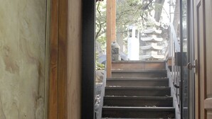 A wooden staircase leading to a traditional Japanese entrance with a green mat at the bottom. - Jiwoljang Guest House (Seoul)