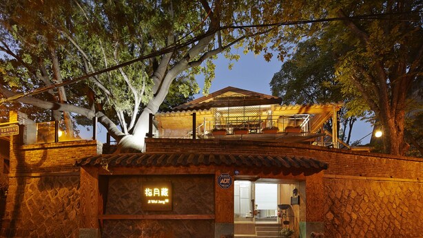 A traditional Korean-style building with a stone facade, a wooden entrance, and a sign in Korean. - Jiwoljang Guest House (Seoul)