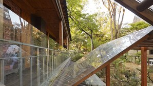 A modern outdoor staircase with a glass balustrade leading to a wooden deck. - Jiwoljang Guest House (Seoul)