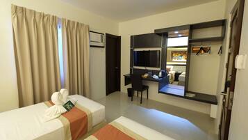 A hotel room with two beds, a desk, a chair, a TV, and a mirror.