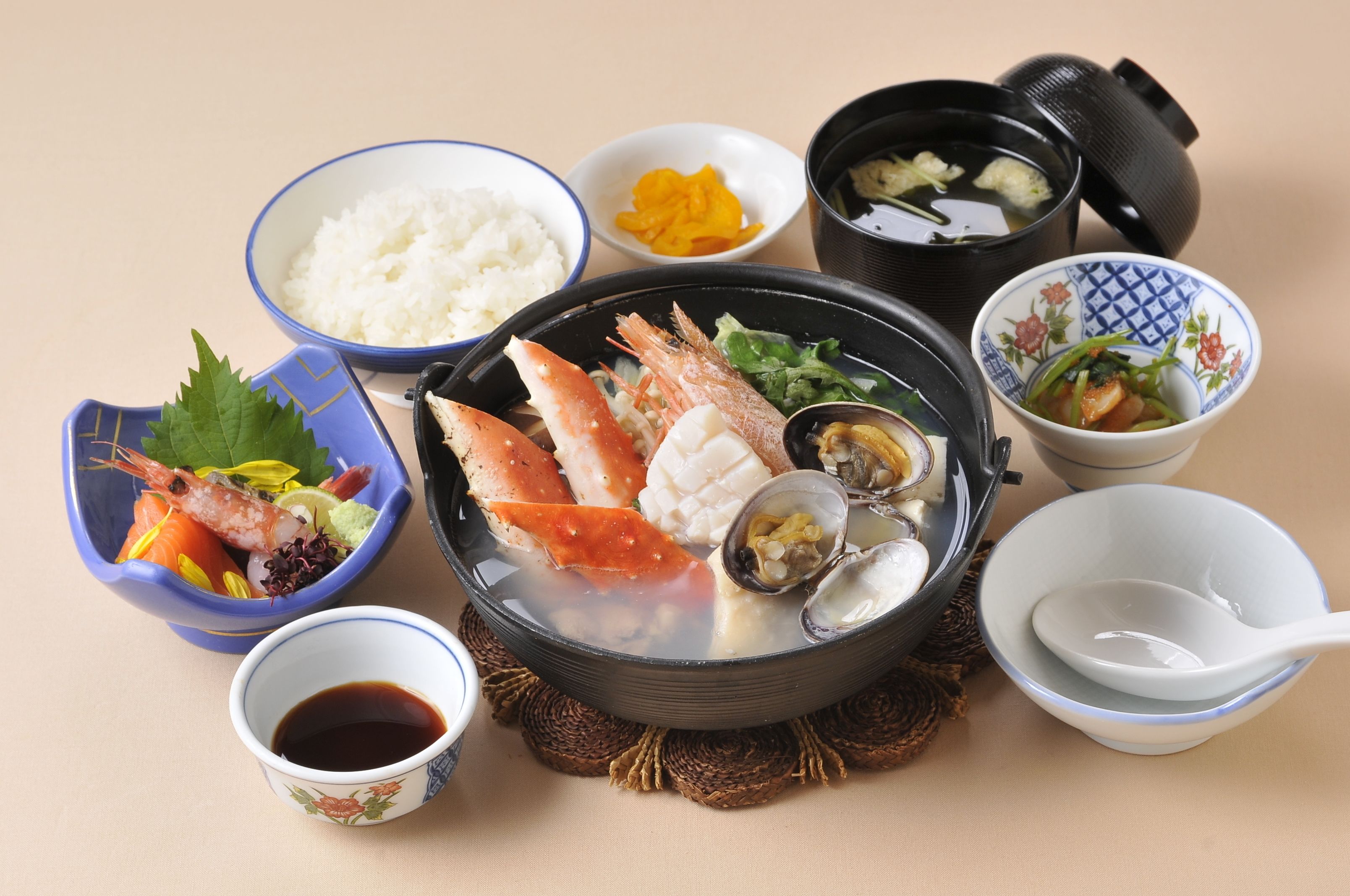 Diversos platos japoneses, como arroz, mariscos y sopa, dispuestos sobre una mesa.