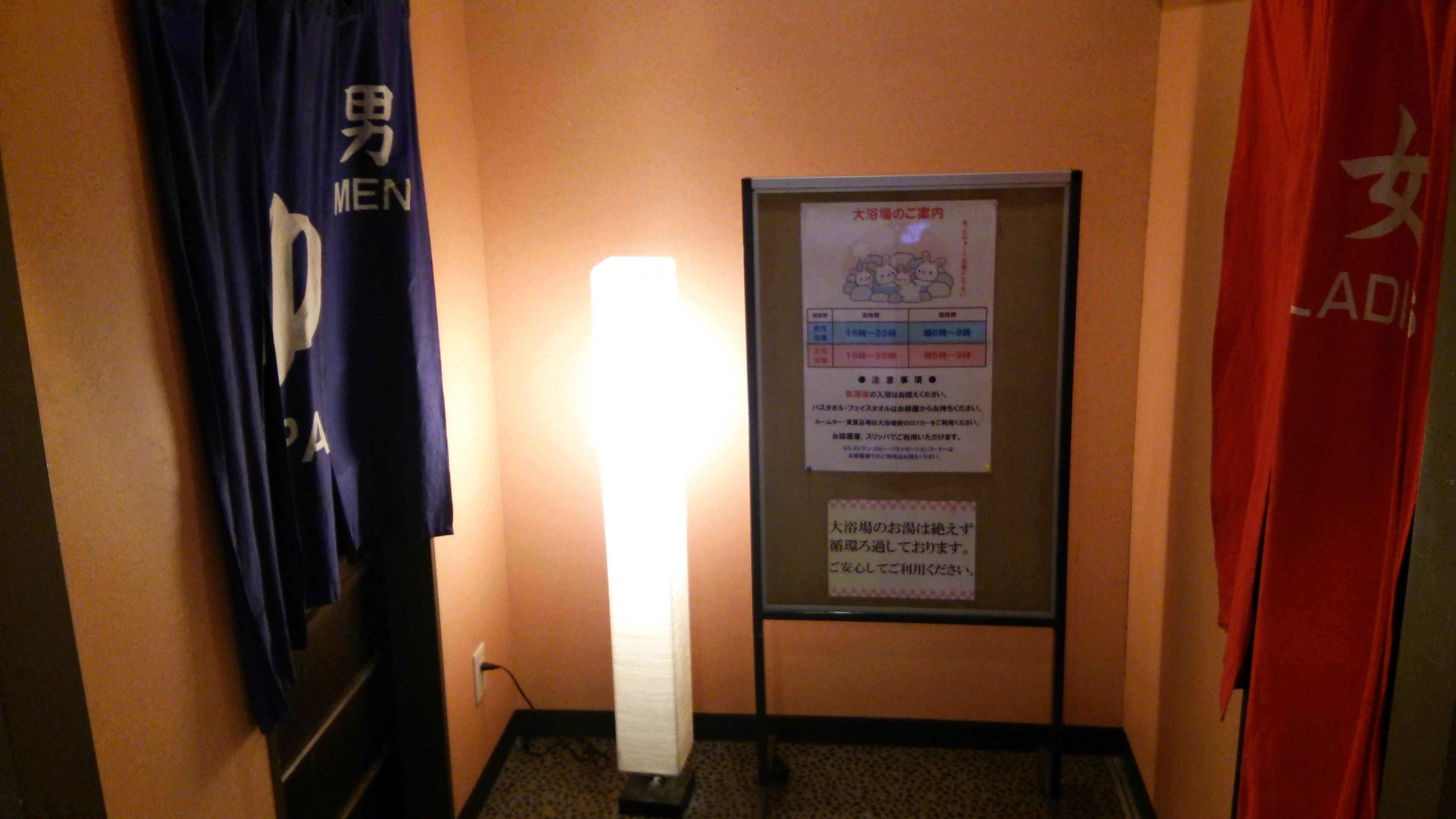 Un pasillo con un cartel en la pared, una lámpara y un letrero con texto en japonés.