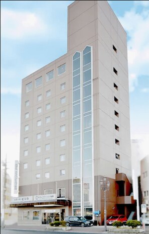 A tall, modern building with a central glass facade and multiple floors.