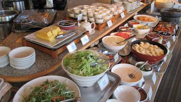 Un bufé con diversos platos y tazones de comida, incluyendo ensaladas y sopas.