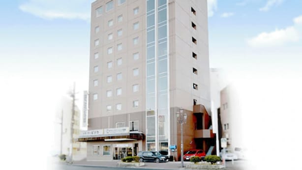 Un hotel moderno con una estructura alta y rectangular, varios pisos y una entrada central con área cubierta.