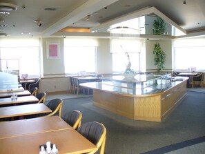 A spacious dining area with a central island, multiple tables, and chairs.